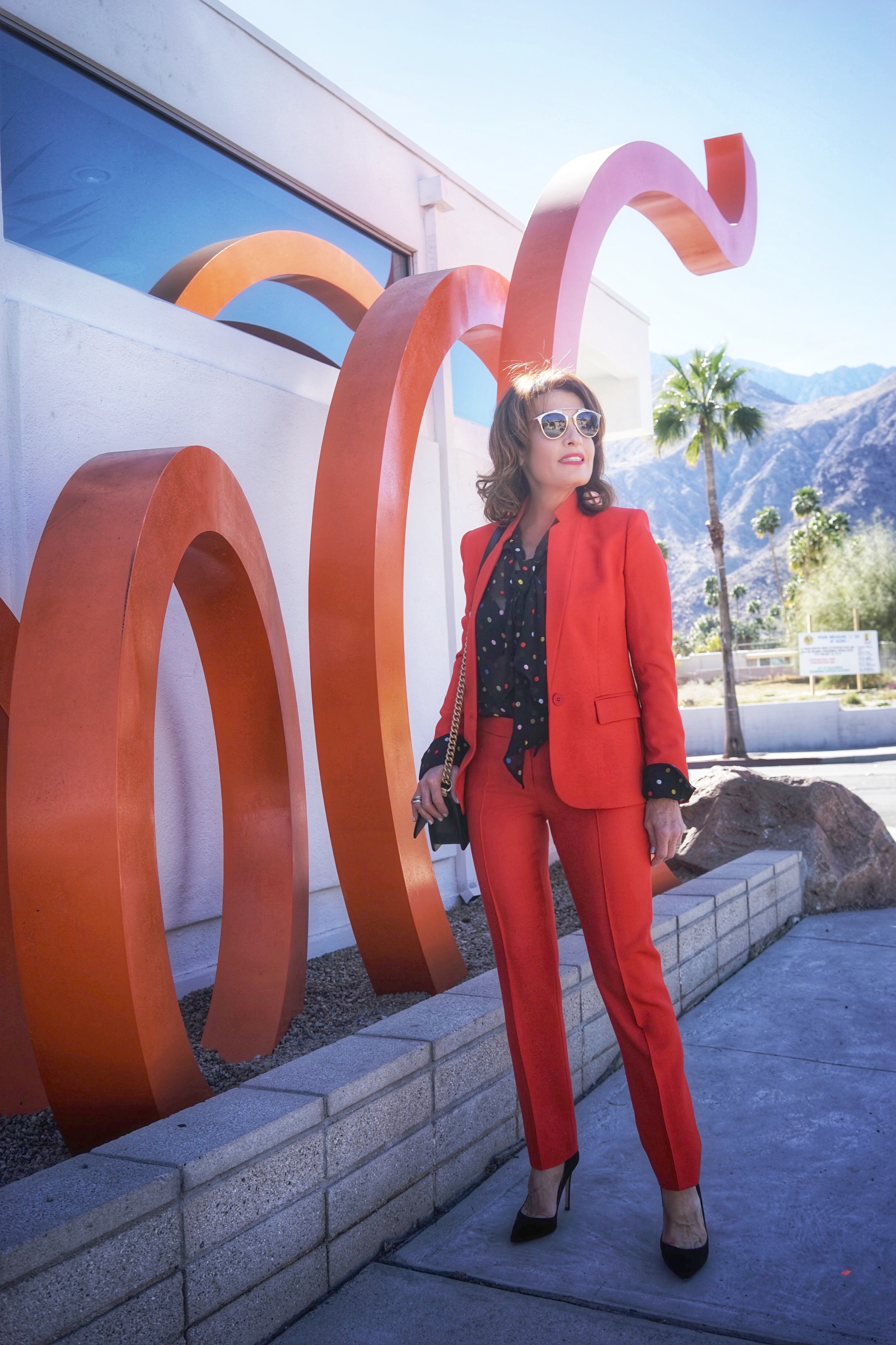  Stella McCartney jacket and pants, Givenchy blouse, Natori bra, Chanel handbag, Gianvito Rossi heels, Christian Dior shades.